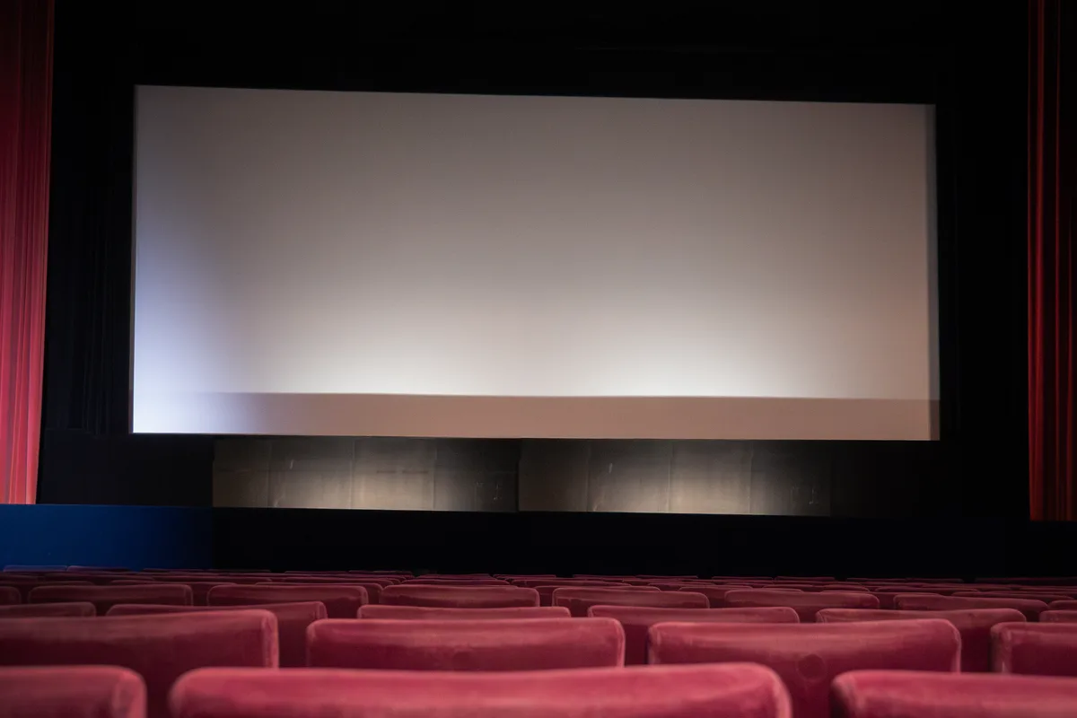 Blick in einen Kino-Saal mit bordeauxroten Sesseln.